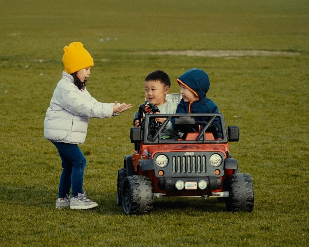 Three children enjoy a sunny day with a toy jeep in an Oakville, Ontario park.